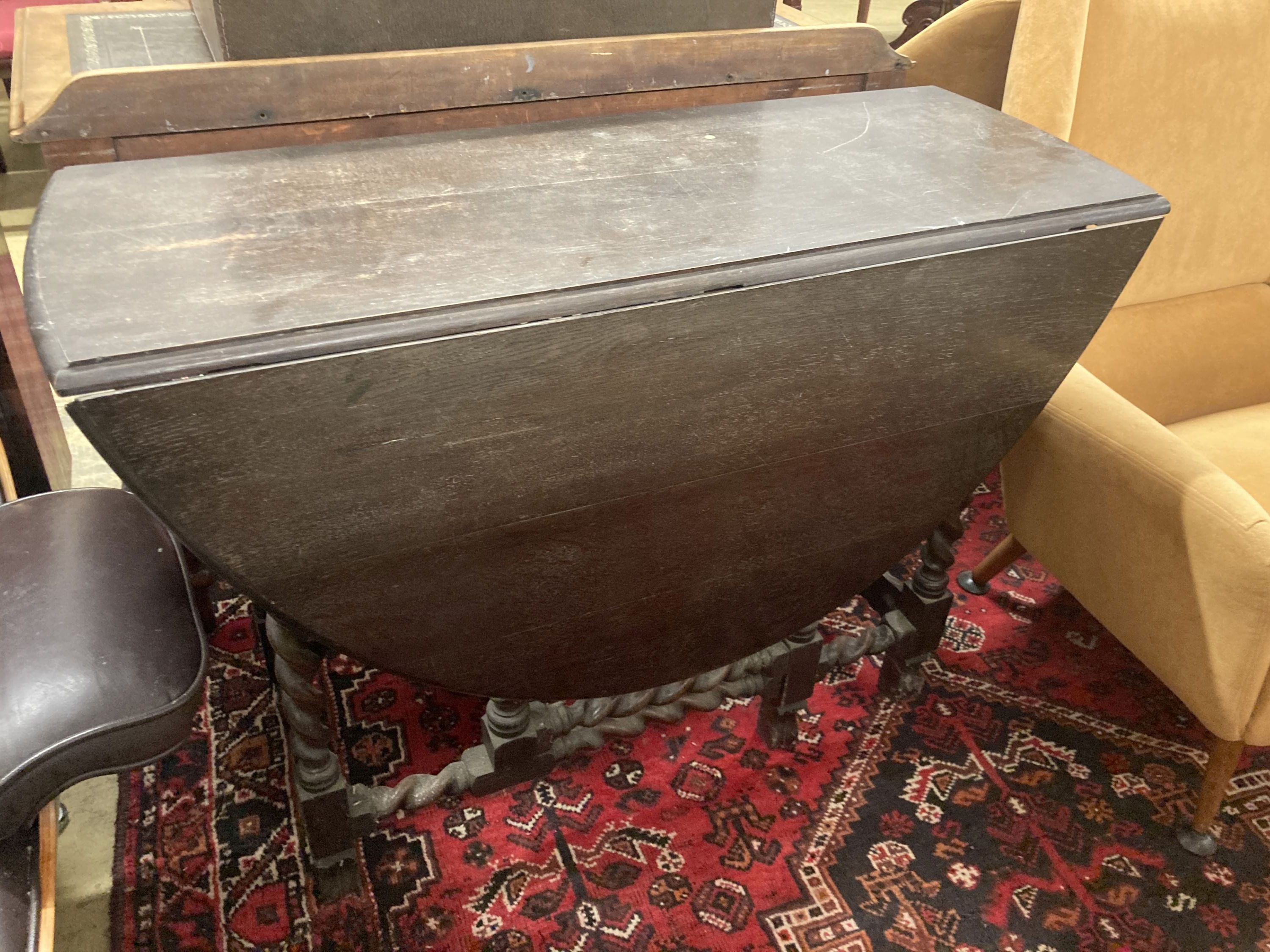 A 1920's oak topped gateleg dining table, on spiral twist legs, width 106cm, depth 40cm, height 76cm